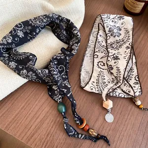 Bohemian paisley print scarves with wooden beads and metal charms on a rustic table