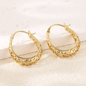 Macro detail of gold vintage geometric oval hoop earrings with intricate hollow patterns