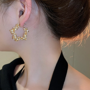 Detailed view of large gold star-shaped hoop earrings with sparkling pave-set zircons