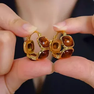 Macro view of 18K gold plated hoop earrings with amber resin inlays for women