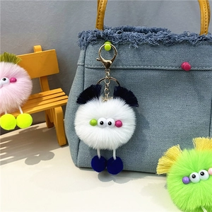Close-up of colorful furry monster bag charms hanging on a blue denim handbag