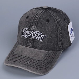 Close-up of Keeplucky embroidery on washed black denim baseball cap with tag