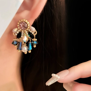 Detailed close-up of vintage gold drop earrings with colorful crystals and white pearl