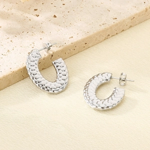 Fashionable C-shaped silver stainless steel earrings with scale texture on stone background