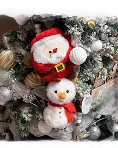 Close-up of Santa and snowman plush toys hanging on a snowy Christmas tree decoration
