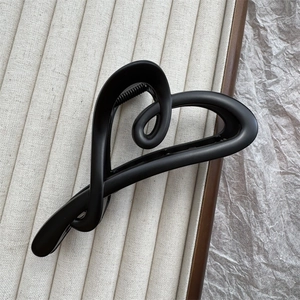 Detail shot of a matte black heart-shaped hair claw clip on a minimalist jewelry tray