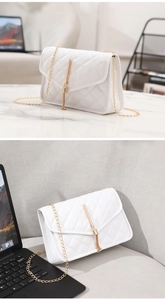 Detail of white quilted crossbody bag featuring a gold chain strap and tassel lock closure