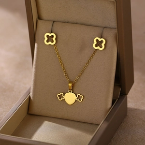 Detailed close-up of golden clover necklace and stud earrings in a jewelry gift box