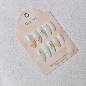 Detailed macro view of sea-themed press-on nails with 3D pearls and starfish patterns