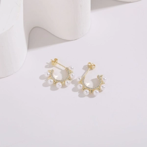 Gros plan sur les boucles d'oreilles perles dorées en C avec zircon et design rayonnant