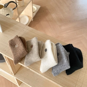 Close-up of five pairs of warm knitted socks with delicate flower embroidery details