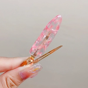 Pink translucent acetate hair clip with floral patterns and golden duckbill metal grip