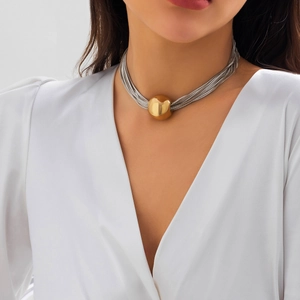 Close-up of layered silver chain necklace featuring a large glossy gold ball pendant