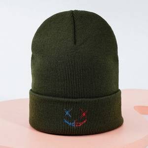 Détail du visage brodé bicolore sur un bonnet en maille de couleur vert olive foncé