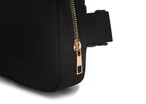 Close-up of golden metal zipper and high-quality waterproof black nylon fabric on waist bag