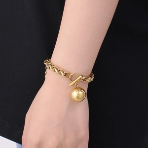Close-up of golden hollow sphere charm and OT toggle clasp on a stainless steel chain
