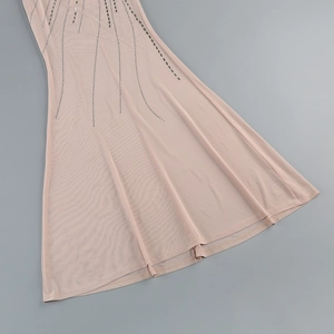 Detailed view of sheer mesh fabric with sparkling rhinestone rows on a nude fish tail dress