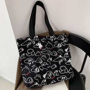 Close-up of black canvas tote featuring white hand-drawn dog patterns on a stylish coat