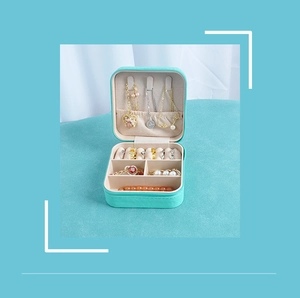 Detail view of open mint green jewelry box showing necklace hooks and ring compartments