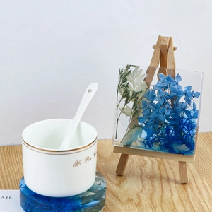 Detail of square resin floral block with blue hydrangea on small wooden easel