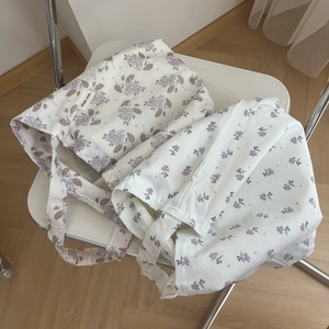 Floral cotton underarm bags in cream and purple floral patterns displayed on a chair