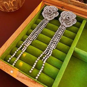 Vue macro de boucles d'oreilles fleur à pompons argentés sur un coffret en velours