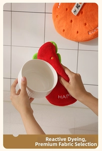 Detailed view of thick fruit-shaped coral fleece kitchen gloves being used for heat protection