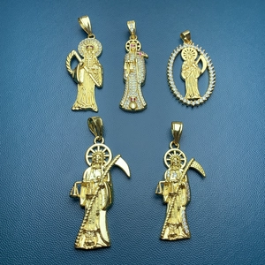 Macro view of five gold-plated Santa Muerte pendants with zircon stones on blue leather