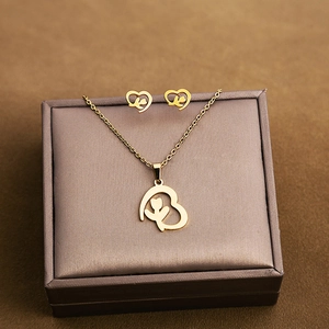 Detail view of hollow heart necklace and stud earrings with floral pattern in gold finish