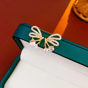 Macro detail of gold plated butterfly earrings with sparkling cubic zirconia on a jewelry box
