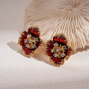 Detail of vintage gold flower earrings with red enamel and sparkling rhinestones