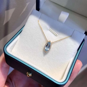 Gros plan d'un collier serti d'une pierre bleu clair marquise dans un écrin en velours
