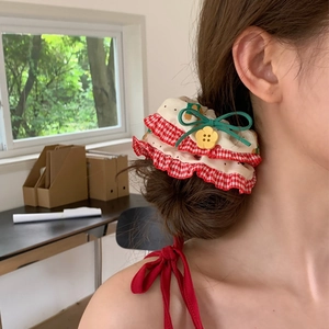 Detail of floral scrunchie with red plaid ruffles, green bow, and a small yellow flower