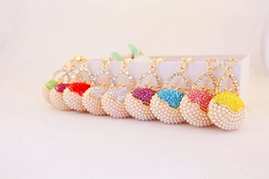 Detailed view of colorful rhinestone and pearl handbag-shaped metal keychain charms