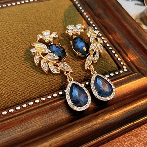 Détail macro de boucles d'oreilles vintage en or avec cristaux bleu foncé sur velours