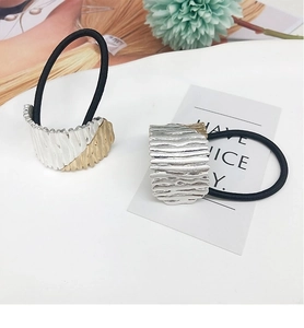 Detail view of gold and silver textured alloy metal charms on high-elastic hair bands