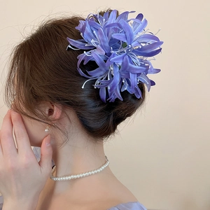 Détail de la pince à cheveux fleurie en tissu violet avec des étamines blanches fines