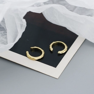 Detail of gold ear cuffs with hammered texture and non-pierced C-shaped open design