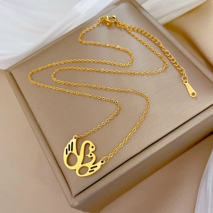 Detail of gold swan heart pendant on beige jewelry box with silk background texture