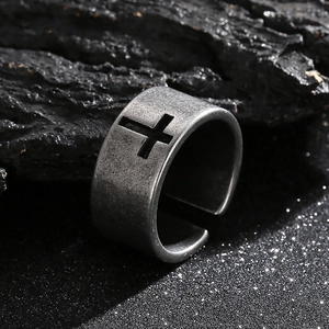 Close-up of vintage hollow cross ring on dark charcoal and sparkling dust background