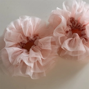 Close-up of pink layered lace scrunchies with sheer mesh texture and ruffle details