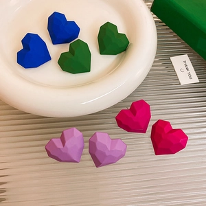Macro shot of colorful matte heart earrings on a ceramic dish with decorative accessories