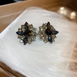 Close-up of vintage floral earrings with black crystals and champagne rhinestones on fur