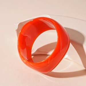 Macro detail of thick orange acrylic resin bangle showing cloud-like marble texture