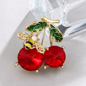 Macro shot of red cherry brooch with green leaves and a small golden bee detail