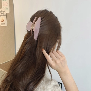 Detail of pink-purple translucent resin hair claw clip worn by a model in a side-back view