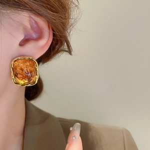 Close-up of vintage gold twisted earrings with amber resin on a female model