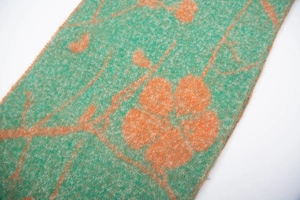 Detail of wool-textured floral scarf with orange flower pattern and fringe edge