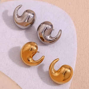Detail of tear-drop shaped polished gold and silver earrings with glossy finish