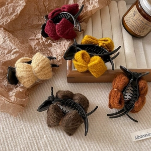 Knitted bow hair clips set in five earthy colors displayed on a wooden tray